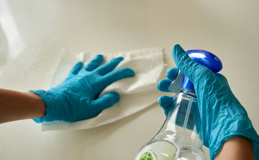 Hände in blauen Handschuhen wischen eine Oberfläche