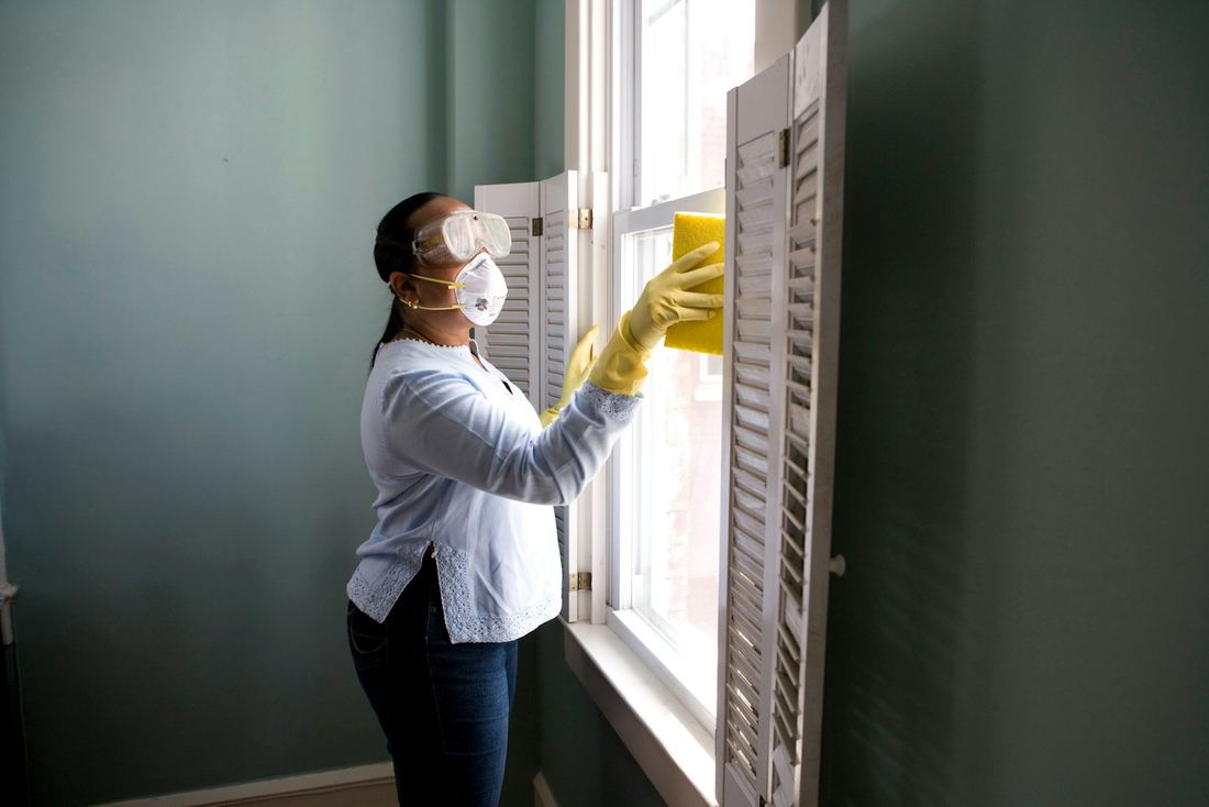 Reinigungskraft putzt ein Fenster in einer Wohnung